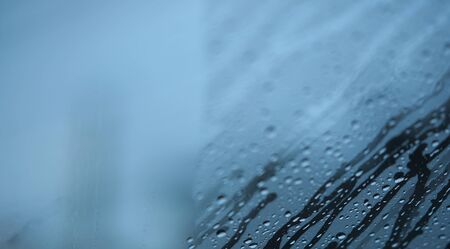 Water stream and dropet on windshield of car in winter