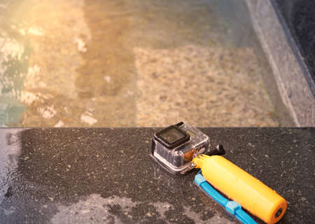 Action camera in waterproof case and floater grip on poolside with sun lightの写真素材