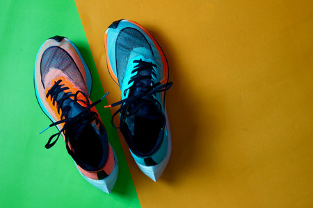 Blue and orange running shoes on green floor with copy test space,top