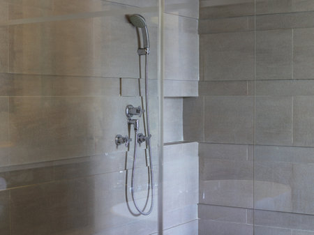 Shower faucet and head on wall with bath mirror enclosureの写真素材