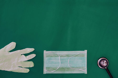 sterile Glove ,mask and stethoscope on green medical dress background