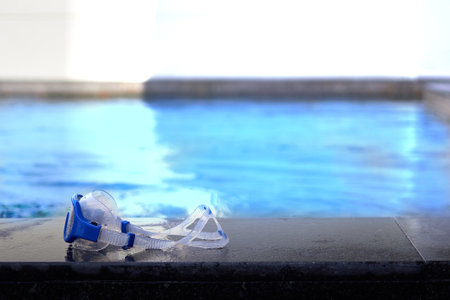 swimming pool with goggles on poolside in summer beach holiday conceptの写真素材
