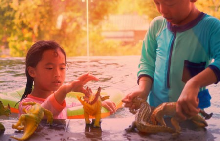 toy for near poolside on blur boy and girl playing in swimming pool background in summer vacation with sun lightの写真素材