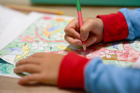 kid hands coloring by color pencil in pajamas sleeves in covid-19 quarantine period