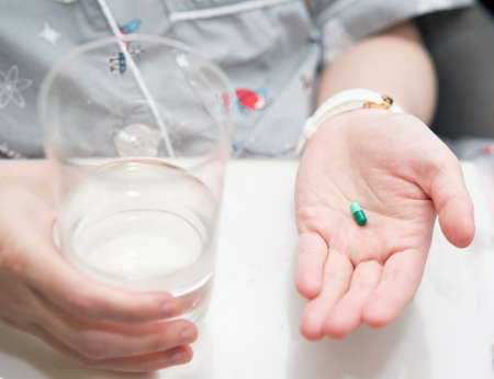 woman hand hold pill supplement antioxidant vitamin mineral capsule with water glass before take medicine capsule for health careの写真素材