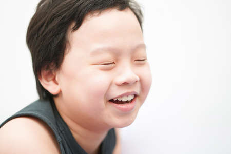 Asia boy child face smile and laugh look away camera head shot portrait with copy space closed eyesの写真素材