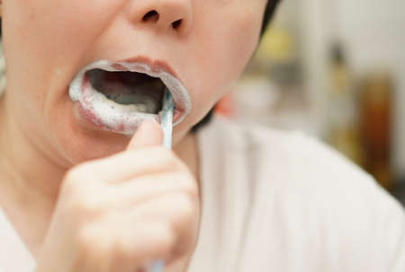 Person use brush to clean oral dental hygiene in mouth for human healthcare concept show lipsの写真素材