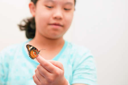 A girl holding up a finger with a butterfly on it. in the living room in the house copy space