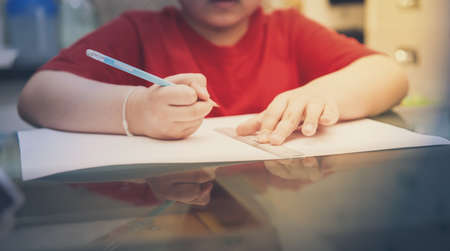 asian boy kid concentrate to write and draw homework before back to school in learning indoor education lessonの写真素材