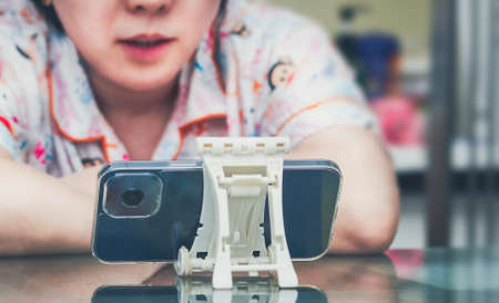 woman watch online internet streaming media on cellphone on stand on table enjoy relax face expressionの写真素材