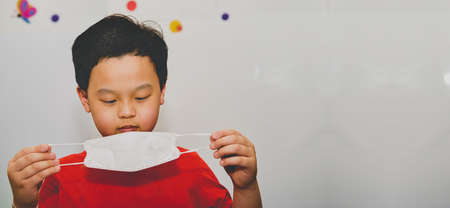 Asia young boy take off protect mask look at camera in room house copy spaceの写真素材