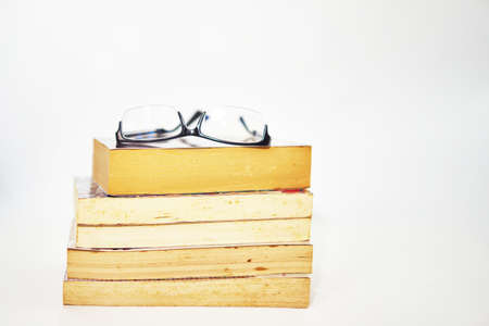 stack of books arranged pile on white background with glasses on topの写真素材