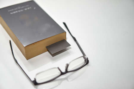 Bookmark in old book on white high angle view with copy space with read glassesの写真素材