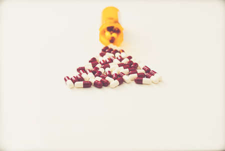 medicine pill tablets spill from medical bottle container on floor in abuse or health vitamins supplement conceptの写真素材