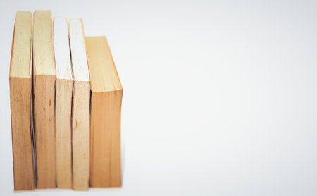 stacks of books arranged horizontally on white background high angle viewの写真素材