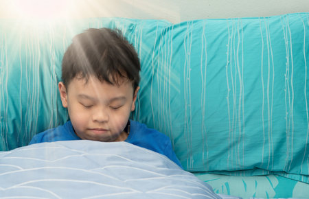 child nap in comfortable pillow with sun light in the morning happy face and freshの写真素材