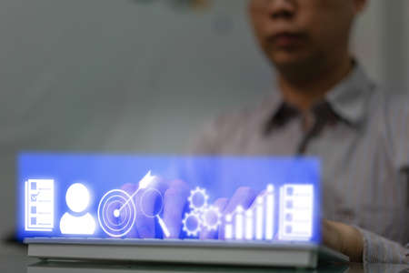 business man finger choose target dart aim option button amoung grae graph chart and goal success strategy achieve way by use technology in marketing competition and great performanceの写真素材