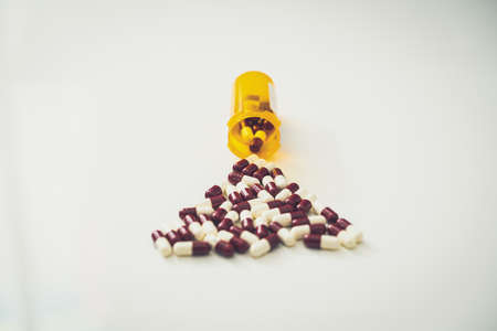 medicine pill tablets spill from medical bottle container on floor in abuse or health vitamins supplement conceptの写真素材