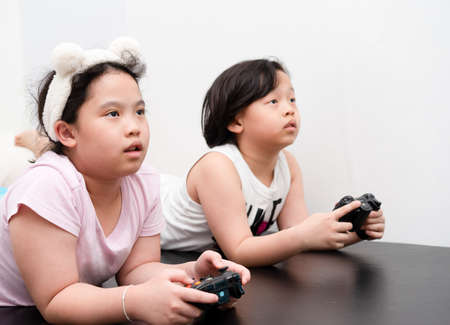 asian children play video game by controller in homeの写真素材