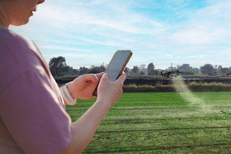 Woman using a mobile phone in a farm, surrounded by farm, control Agriculture Petrol Drone Sprayer .の写真素材