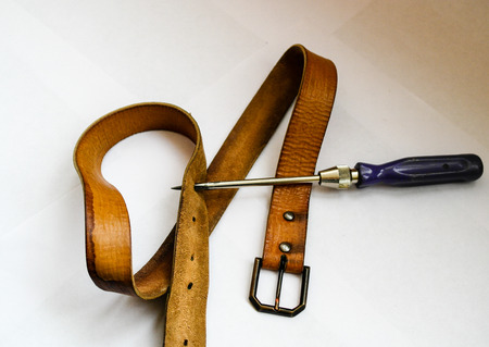 to make a new hole in the belt to tighten their beltsの写真素材