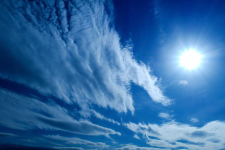 the Sun and white fluffy clouds on a blue skyの写真素材