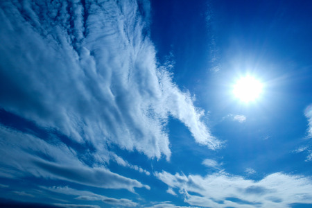 the Sun and white fluffy clouds on a blue skyの写真素材