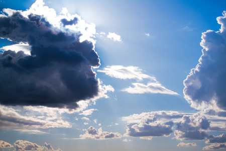 Sun and White and dark Cumulus clouds on a blue skyの写真素材