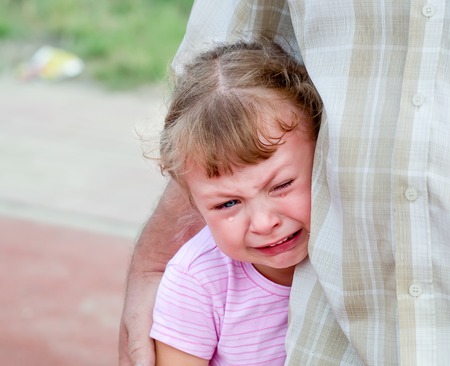 defenseless little girl crying under the protection of the parentの写真素材