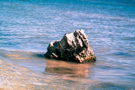 Lone stone sticks out of blue waters against the background of the horizonの写真素材