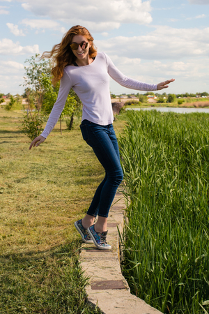 redheaded model is teetering on the parapetの写真素材