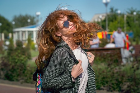 Wind waving red haired girl in sunglasses