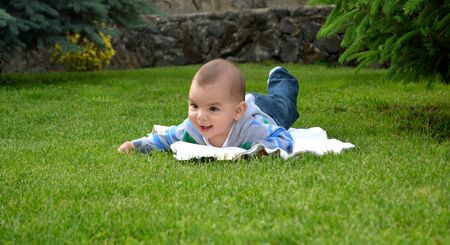 Happy toddler boy playing on green grass. Smiling baby boyの写真素材
