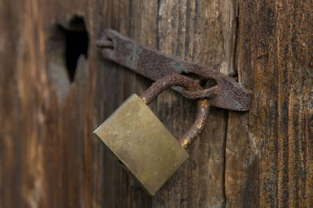 Old window with closed woody shutter and old rust padlock