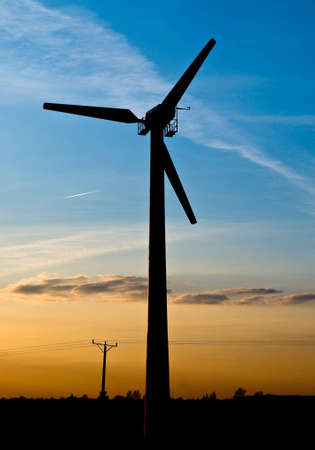 Wind turbine on sunset and blue sky.