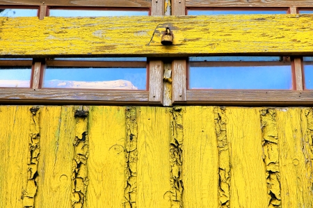 Old window yellow wall closed woody shutter and old rust padlockの写真素材