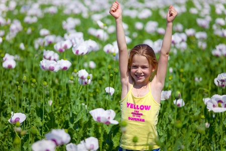 Young girl with hands up in field of white poppy の写真素材