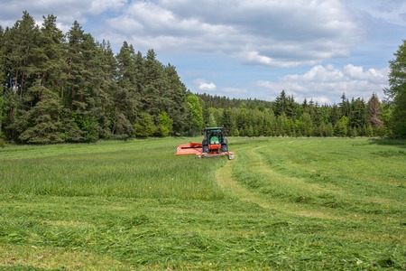 Image of a tractor on meadow. Early grass cutting for BIOGAS productionの写真素材
