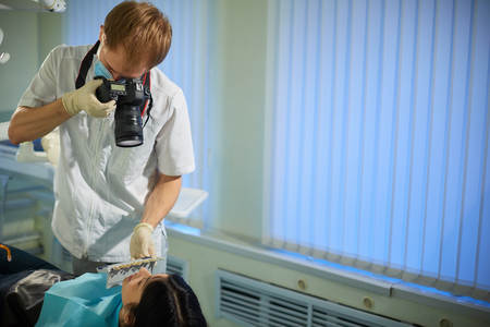 Dentist photographs the teeth of a young woman and selects the color of the veneersの写真素材
