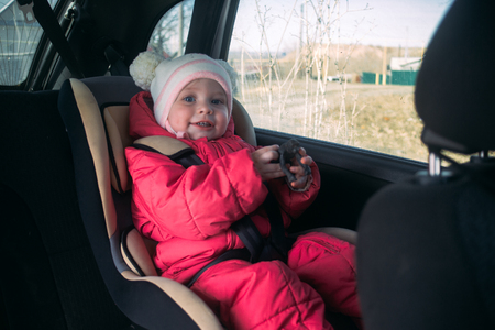 A small one-year-old child sits in a car seat And looks out the windowの写真素材