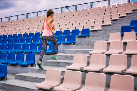 Beautiful muscular girl running around the stairs at the stadium. Crossfit, fitness, healthy lifestyleの写真素材