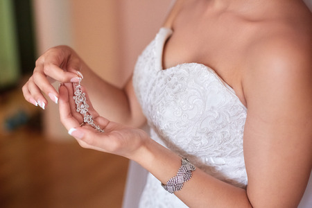 A beautiful bride in a long dress at the hotel and waiting for the groom. jewels of the brideの写真素材