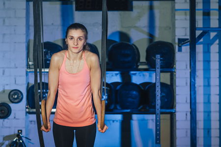 Girl doing exercises on the rings in the gymの写真素材