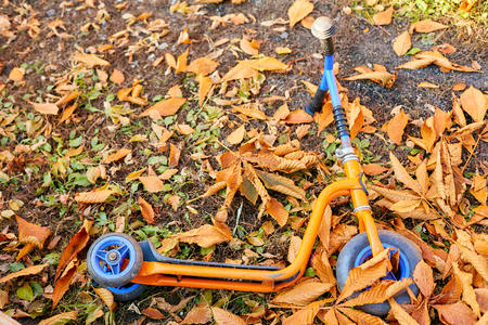 childrens scooter lies on a playground in yellow leaves