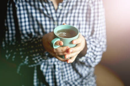 Womens hands hold a cup of tea, toningの写真素材