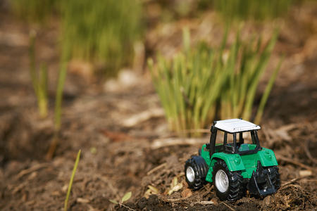 toy tractor on green grass background . Spring sowing worksの写真素材