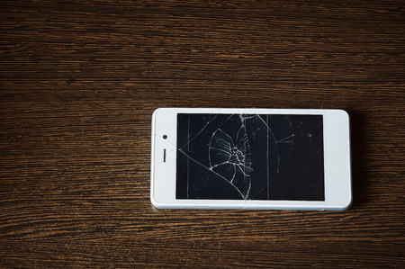 Smartphone with broken screen on the wooden tableの写真素材