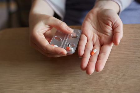 a young woman holds a red and white pill. Taking care of your health