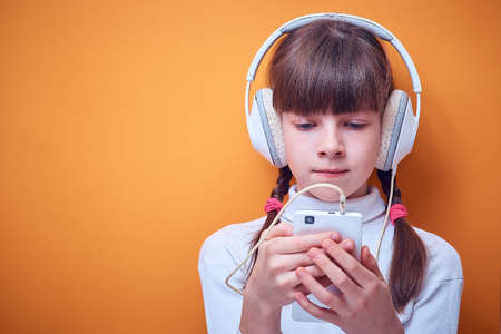 leisure and entertainment , Caucasian teen girl listening to music with headphones using the phone on a colored background, a place for textの写真素材
