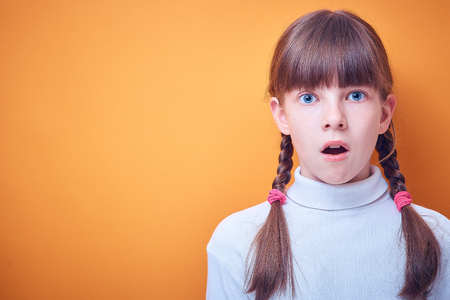 scared and surprised Caucasian teen girl on colored background, place for textの写真素材